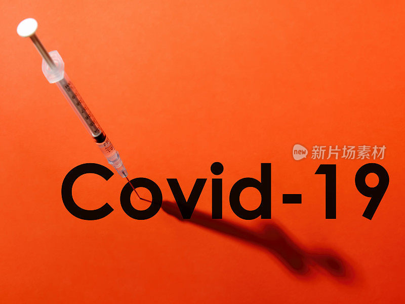 注射器上的针头穿过单词COVID-19 (COVID-19)中的字母“o”的中心。